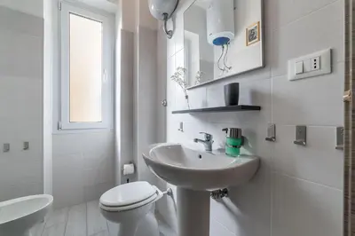 a white bathroom with a toilet and a sink at San Paolo Steampunk Flat in Rome