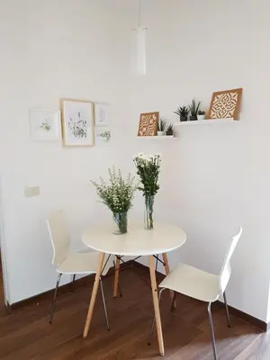a white table with white chairs and a vase of flowers at Vatican Home in Rome - Suite St. Peter's View in Rome