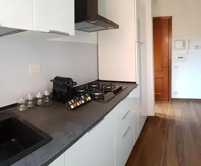 a kitchen with white cabinets and a black counter top at Vatican Home in Rome - Suite St. Peter's View in Rome