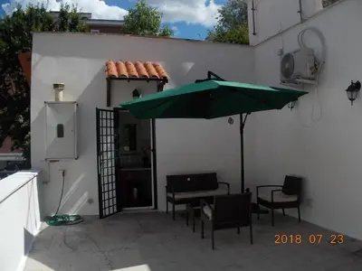 a patio with a table and a green umbrella at L'attico di Val. in Rome