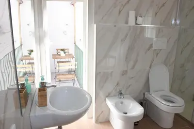 a white bathroom with a toilet and a sink at Santa Maria Suites in Rome
