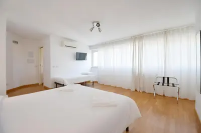 a white bedroom with two beds and a window at Guesthouse Vassallo Due in Rome