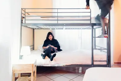a woman sitting on a bed in a bunk bed at The Beehive Hostel in Rome