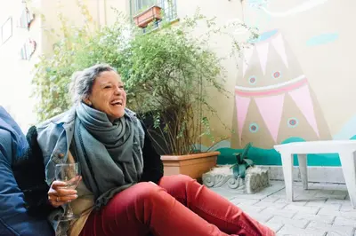 an older woman sitting on a chair with a glass of wine at The Beehive Hostel in Rome