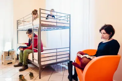 two women sitting in chairs in a room with bunk beds at The Beehive Hostel in Rome