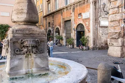 a woman standing next to a fountain in a street at Casa Coronari Holidays in Rome