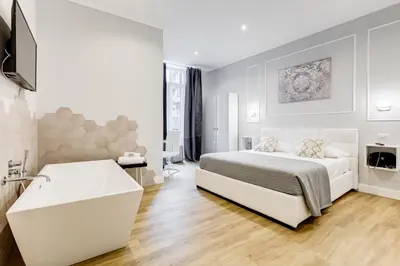 a white bedroom with a bed and a bath tub at Opera Private Suites by Premium Suites Collection in Rome