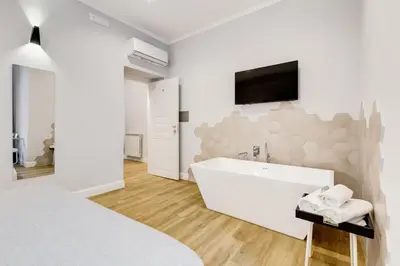 a white bedroom with a tub and a tv on a wall at Opera Private Suites by Premium Suites Collection in Rome