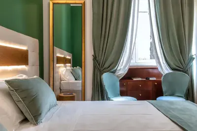 a bedroom with a bed and two blue chairs and a mirror at Hotel Paba in Rome
