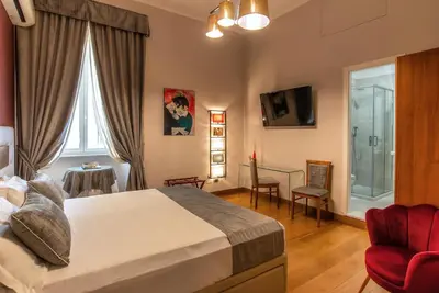 a bedroom with a large bed and a red chair at Hotel Paba in Rome