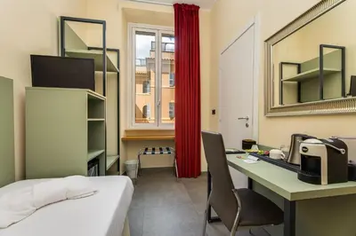 a room with a bed and a desk and a window at Seven in Rome