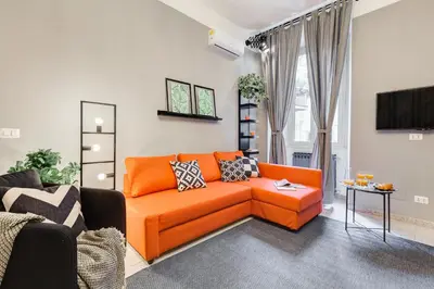 a living room with an orange couch and a tv at TRIDENTE Apartment in Rome