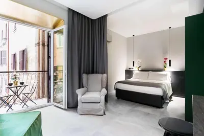 a bedroom with a bed and a chair and a window at Etruscan Luxury Suites in Rome