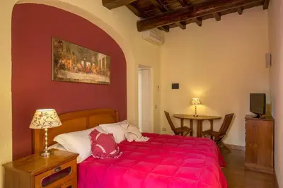 a bedroom with a red bed and a table at Bollo Apartments in Rome