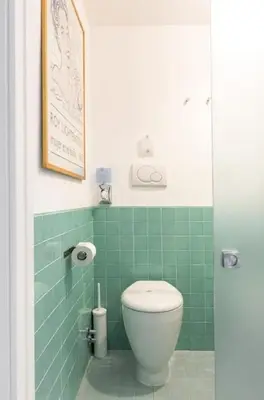 a green tiled bathroom with a toilet in it at Smart Lodgings Plus in Rome
