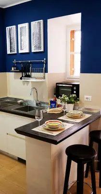 a kitchen with blue walls and a counter with stools at Deco's Place Roma Zoe in Rome