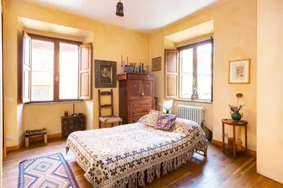 a bedroom with a bed and a dresser and windows at Charming Bright Colosseum apartment in Rome