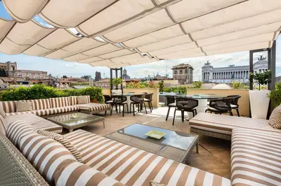 an outdoor patio with couches and a table and chairs at Amazing Penthouse Piazza Venezia in Rome