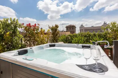 a hot tub with two wine glasses in it at Amazing Penthouse Piazza Venezia in Rome