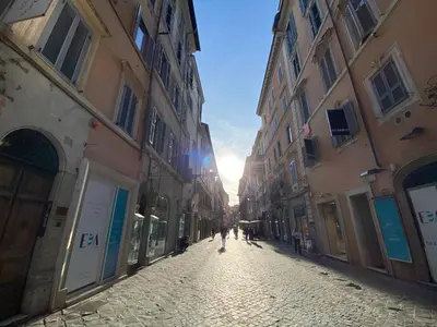 a person walking down a cobblestone street between buildings at Frattina 57 in Rome