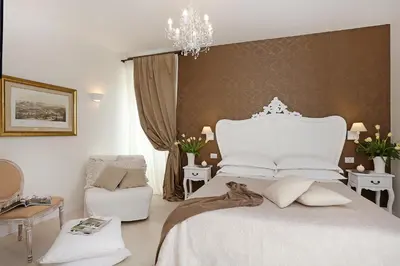 a bedroom with a large white bed and a chair at Daplace - HQH Colosseo in Rome