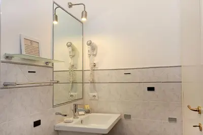 a white bathroom with a sink and a shower at Daplace - HQH Colosseo in Rome