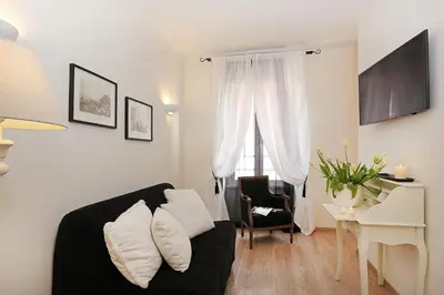 a living room with a black couch and a table at Daplace - HQH Colosseo in Rome