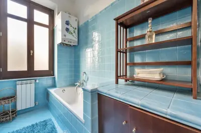 a blue tiled bathroom with a tub and a sink at Re Di Roma Vintage Apartment in Rome