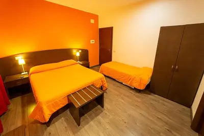 two beds in a room with orange walls and wooden floors at Difronte Ai Musei Vaticani in Rome