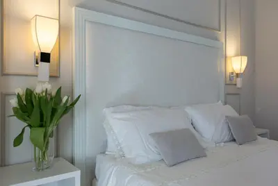 a white bedroom with a white bed with a vase of flowers at Residenza Scipioni Luxury B&B in Rome