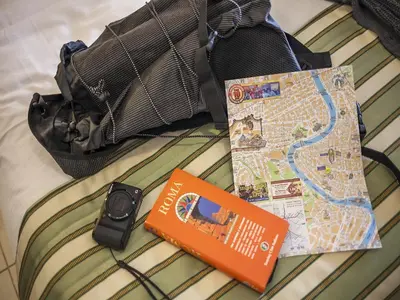 a bag and a cell phone on a bed at Hotel Regina Giovanna in Rome