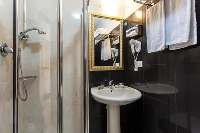 a bathroom with a sink and a shower with a mirror at Hotel Regina Giovanna in Rome