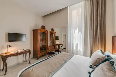 a bedroom with a bed and a desk and a television at Adrianus Hotel in Rome