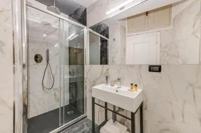 a white bathroom with a shower and a sink at Adrianus Hotel in Rome