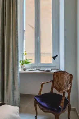 a chair sitting in front of a window with a plant at Adrianus Hotel in Rome
