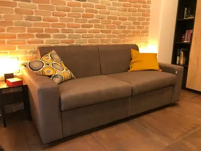 a brown couch in a room with a brick wall at Appartamento in via Licia in Rome