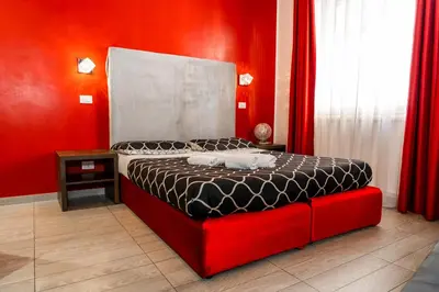 a bedroom with a bed with a red wall at Le Terrazze di San Giovanni in Rome
