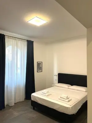 a bedroom with a bed with white sheets and a window at Inn Urbe Colosseo in Rome