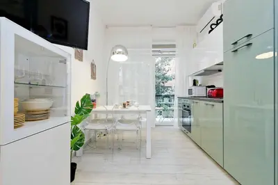 a white kitchen with a table and a dining room at Vaticano terrace: brand new 2 bedrooms 2 bathrooms in Rome