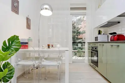 a white kitchen with a table and some chairs at Vaticano terrace: brand new 2 bedrooms 2 bathrooms in Rome