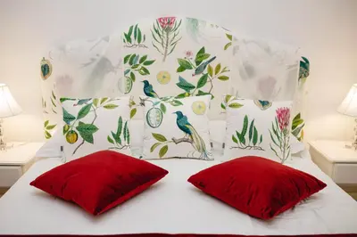 a bed with two red pillows and a floral headboard at Delfini Trevi House in Rome