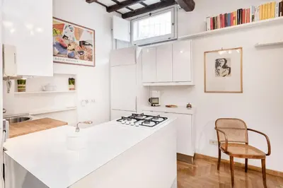 a kitchen with white cabinets and a sink and a chair at Campo de' Fiori Apartment in Rome
