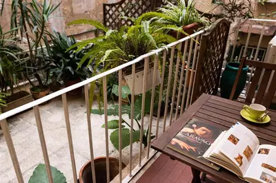 a book on a wooden bench on a balcony with plants at Casa Linnea in Rome