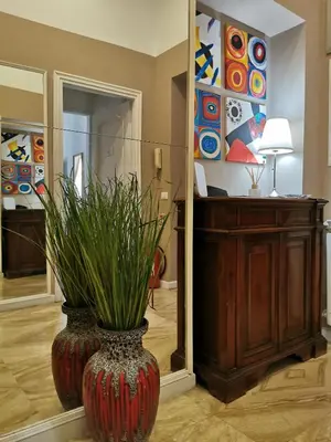 a large red vase with a plant in front of a mirror at 109 SUITES ROMA in Rome