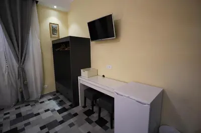 a room with a desk with a tv on the wall at Quest House Lihong in Rome
