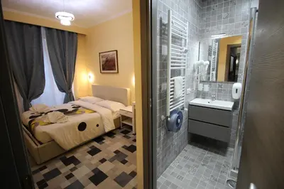 a bedroom with a bed and a bathroom with a sink at Quest House Lihong in Rome