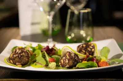 a plate of food with meatballs and salad on a table at Tree Charme Parliament Boutique Hotel in Rome