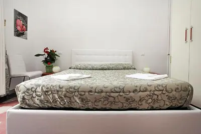 a white bedroom with a bed with a white headboard at Angels In Rome in Rome