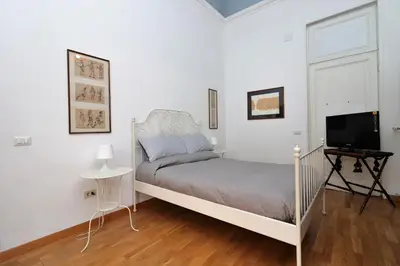 a white bedroom with a bed and a television at Trevi Suite B&B in Rome