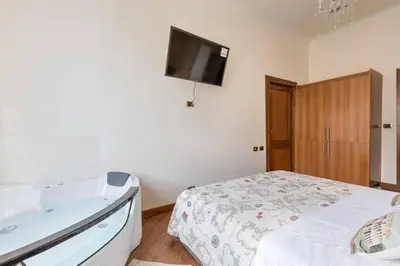 a bedroom with a tub and a bed and a tv at jacuzzi in front of the colosseum in Rome